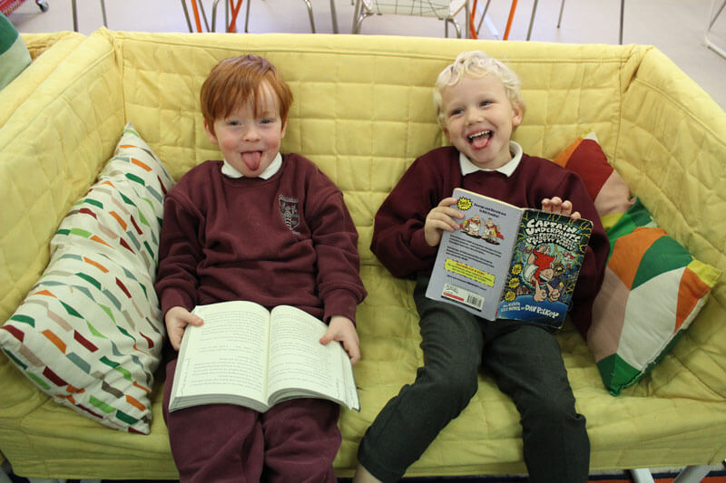 two boys reading on a yellow couch at after school care mullingar the den